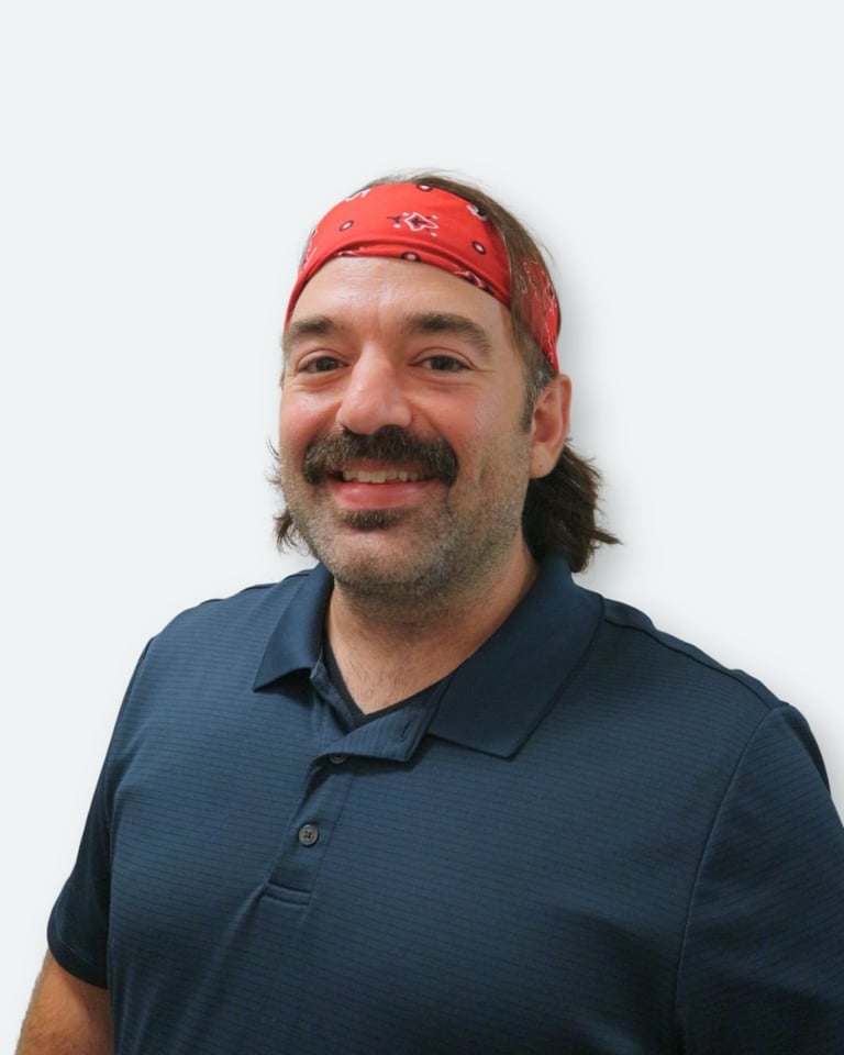 Portrait of a man with a beard wearing a red bandana and dark blue polo shirt against a white background