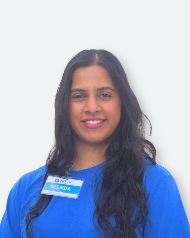 Portrait of a woman with long dark hair wearing a blue shirt with a name badge reading Glenda