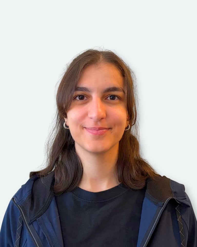 Portrait of a young woman with long dark hair wearing a dark blue shirt and navy jacket against a white background