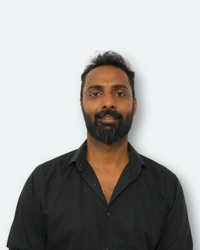 Professional headshot of a man with dark hair and beard wearing a black shirt against a white background