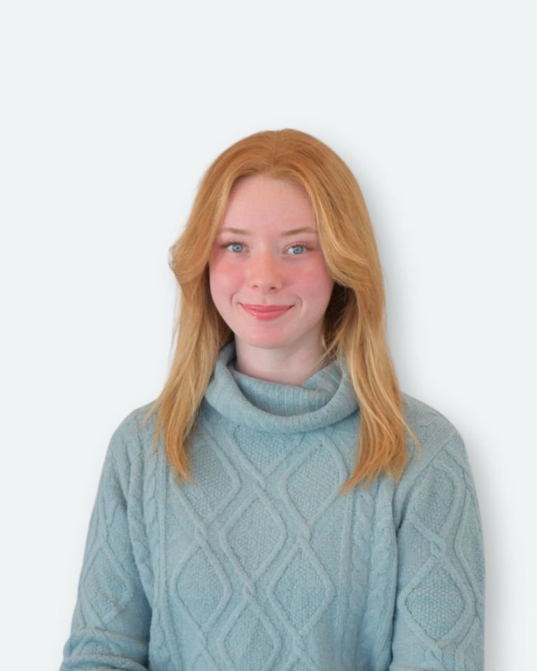 Portrait of a young woman with long reddish-brown hair wearing a gray cable-knit turtleneck sweater against a white background