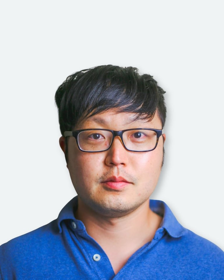 Portrait of a man wearing glasses and a blue shirt against a white background