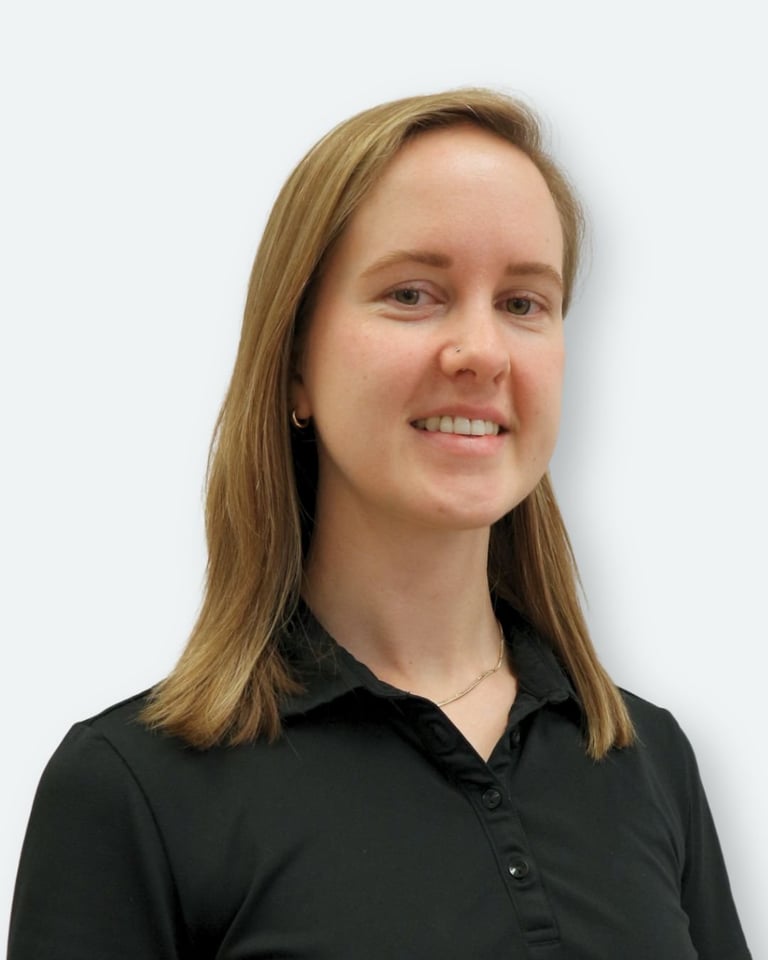 Woman with shoulder-length brown hair wearing a black button-up shirt, smiling at camera against a light gray background