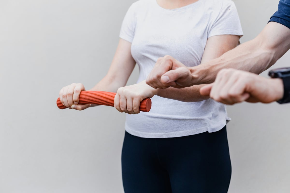 Two peoples hands holding a resistance band together during an exercise or training session.