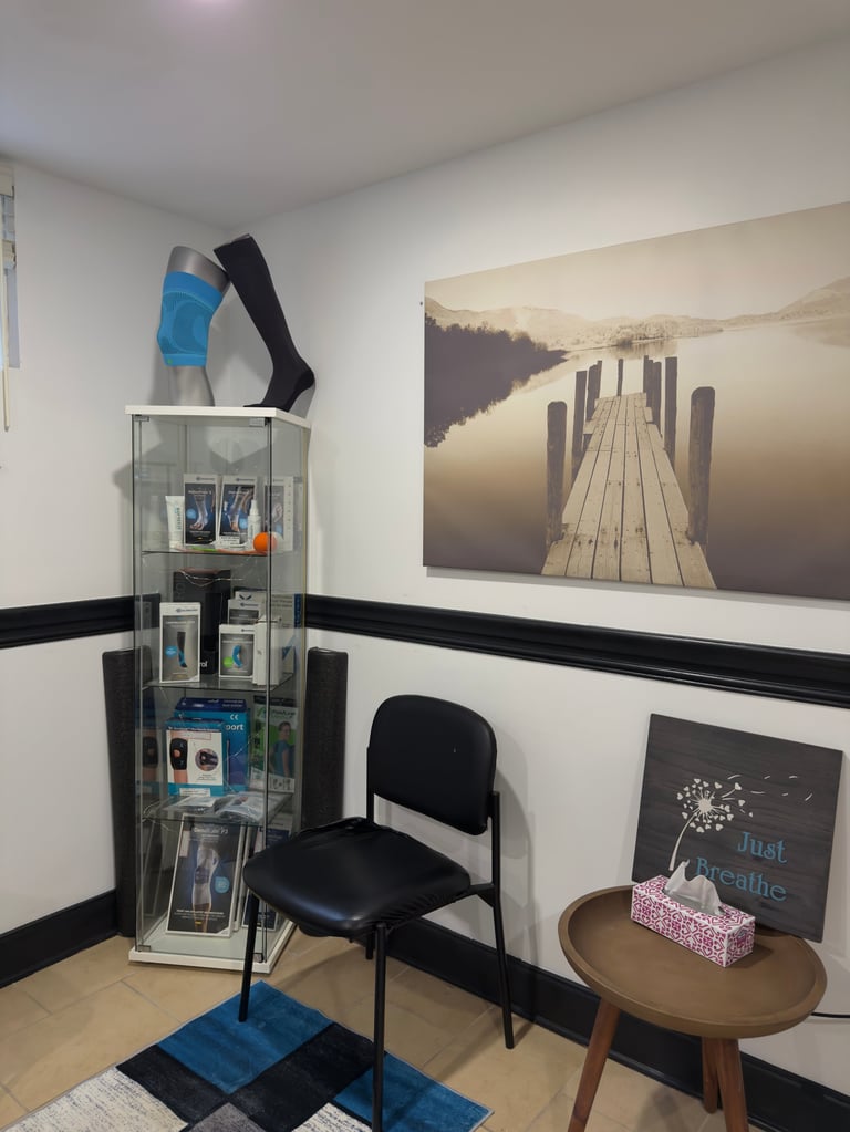 Professional office or retail space with white walls, glass display case, black chair, wooden table with inspirational sign, and landscape photograph on wall