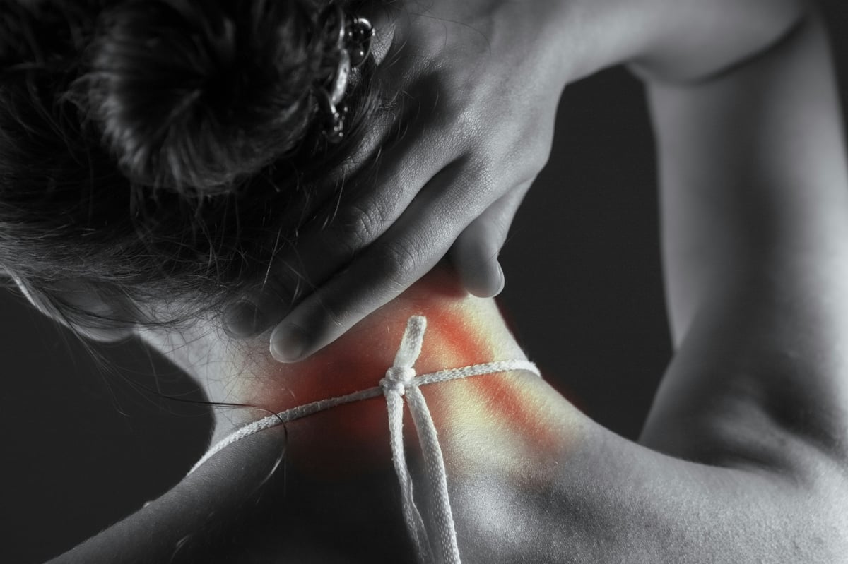 Woman holding neck with red highlighted pain area, black and white image showing neck strain or injury
