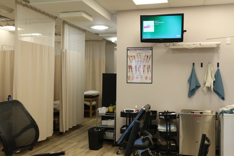 Modern medical clinic interior with examination curtains, wall-mounted monitor, anatomical poster, and medical equipment on wooden flooring