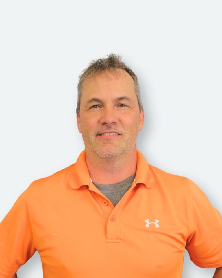 Middle-aged man wearing bright orange Under Armour polo shirt over gray t-shirt, professional headshot against white background