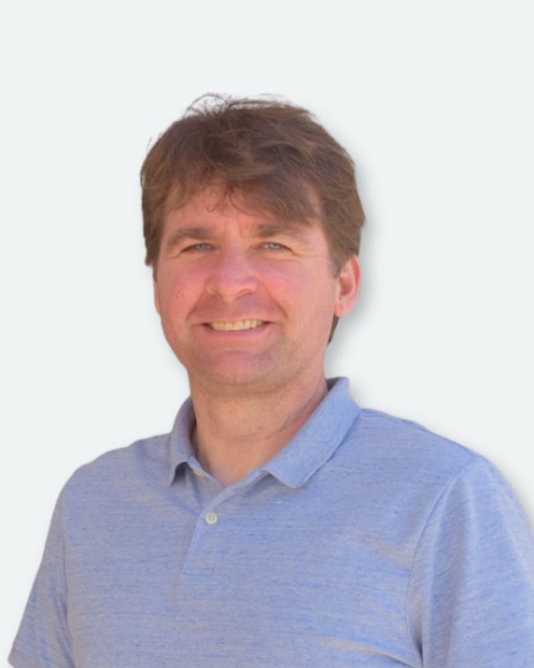 Portrait of a middle-aged man with brown hair wearing a light blue polo shirt against a white background