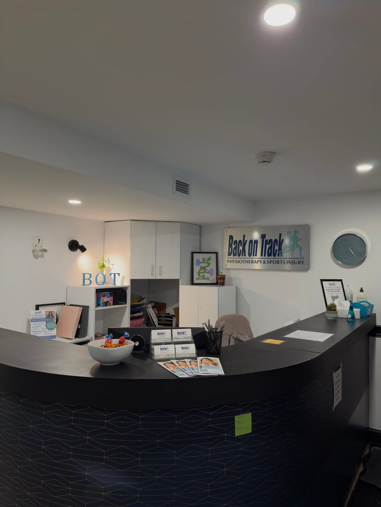 Reception desk with black curved counter, office shelving, and Back on Track sign in modern professional interior space